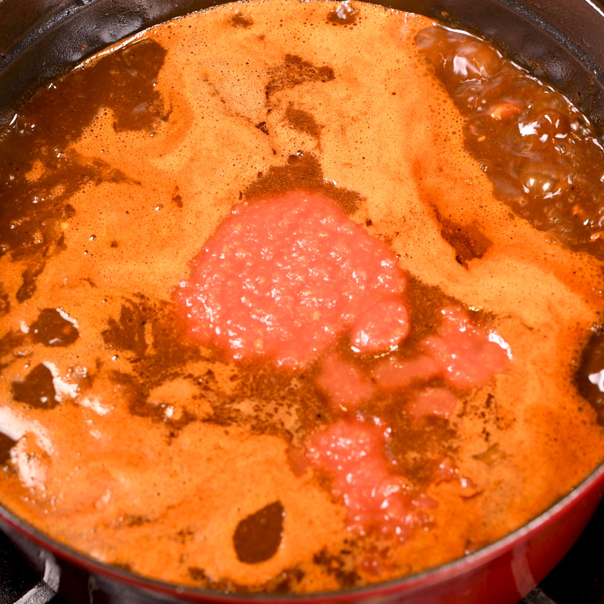 Add the crushed tomatoes and blended chiles to the Dutch oven.