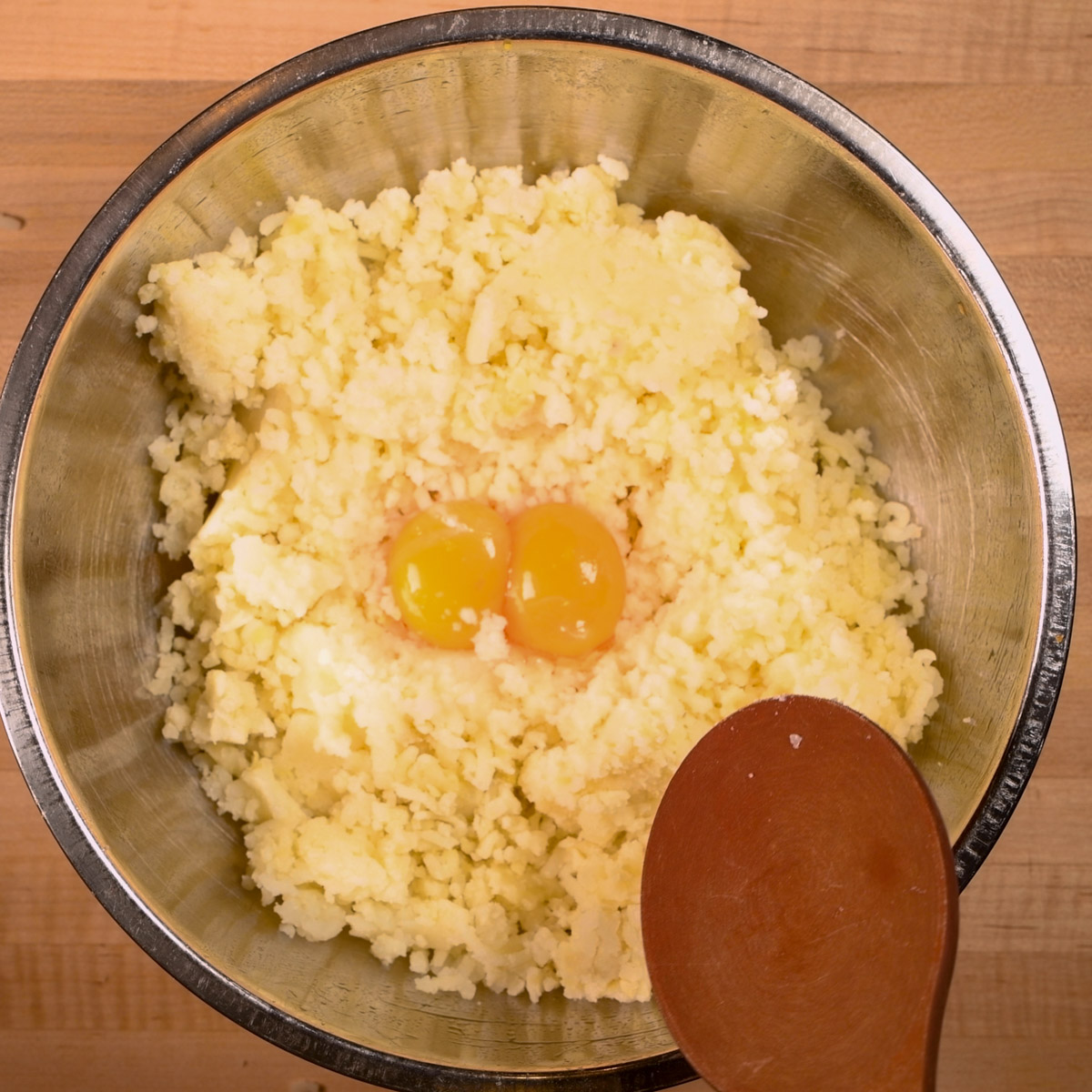 Add the eggs to the riced potatoes.