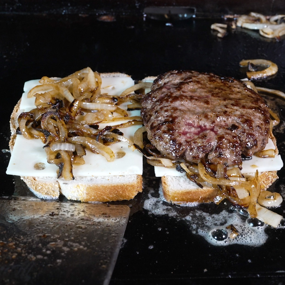 Add onions, Swiss cheese and grilled patty to the rye bread.