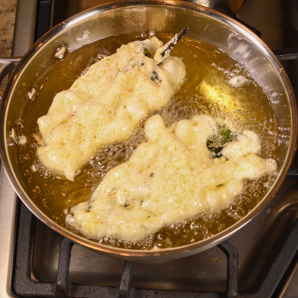 Fry the chile rellenos in hot oil until golden brown.
