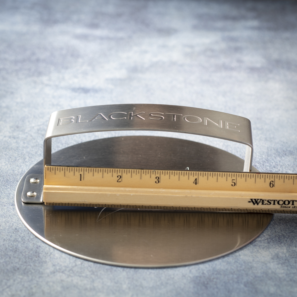 The Blackstone stainless steel burger press has a wide handle with 5.5 inches of clearance.