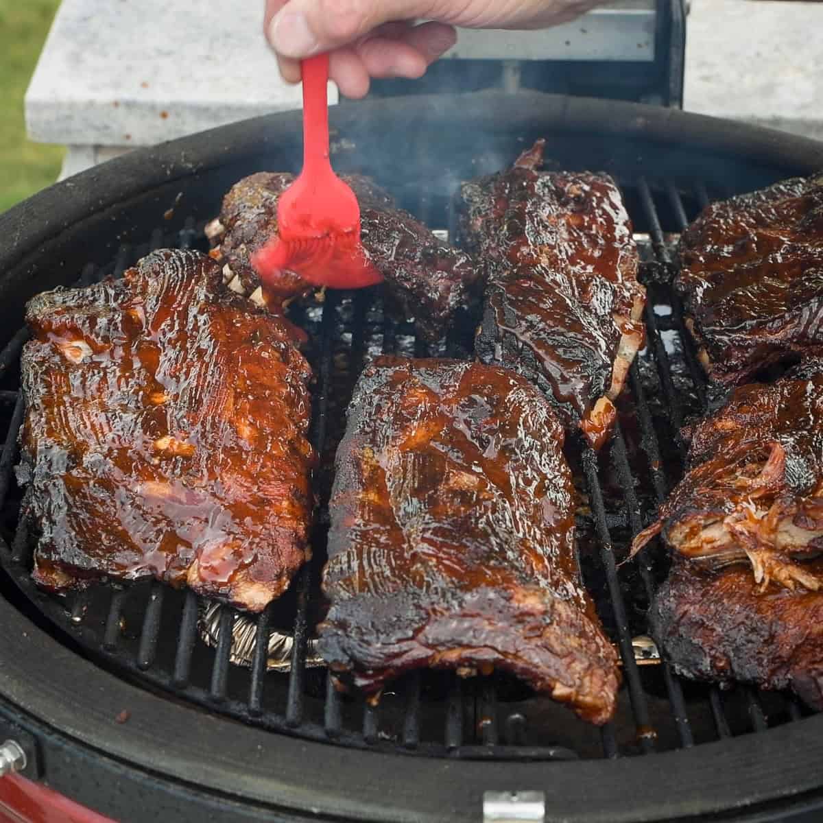 Brushing BBQ onto baby back ribs.