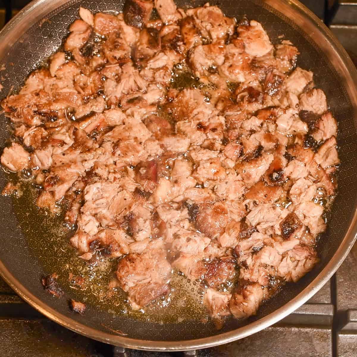 Sear carnitas meat in a hot skillet.