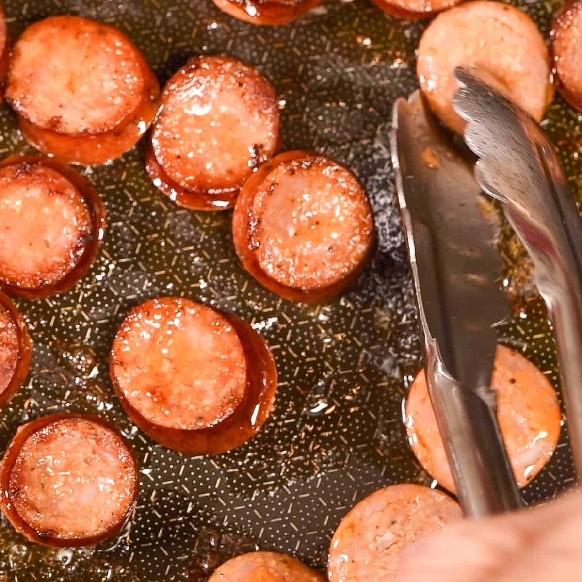 Brown the andouille sausage in a fry pan.