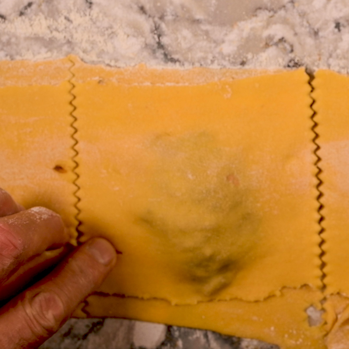 Add top sheet of pasta and cut the ravioli.