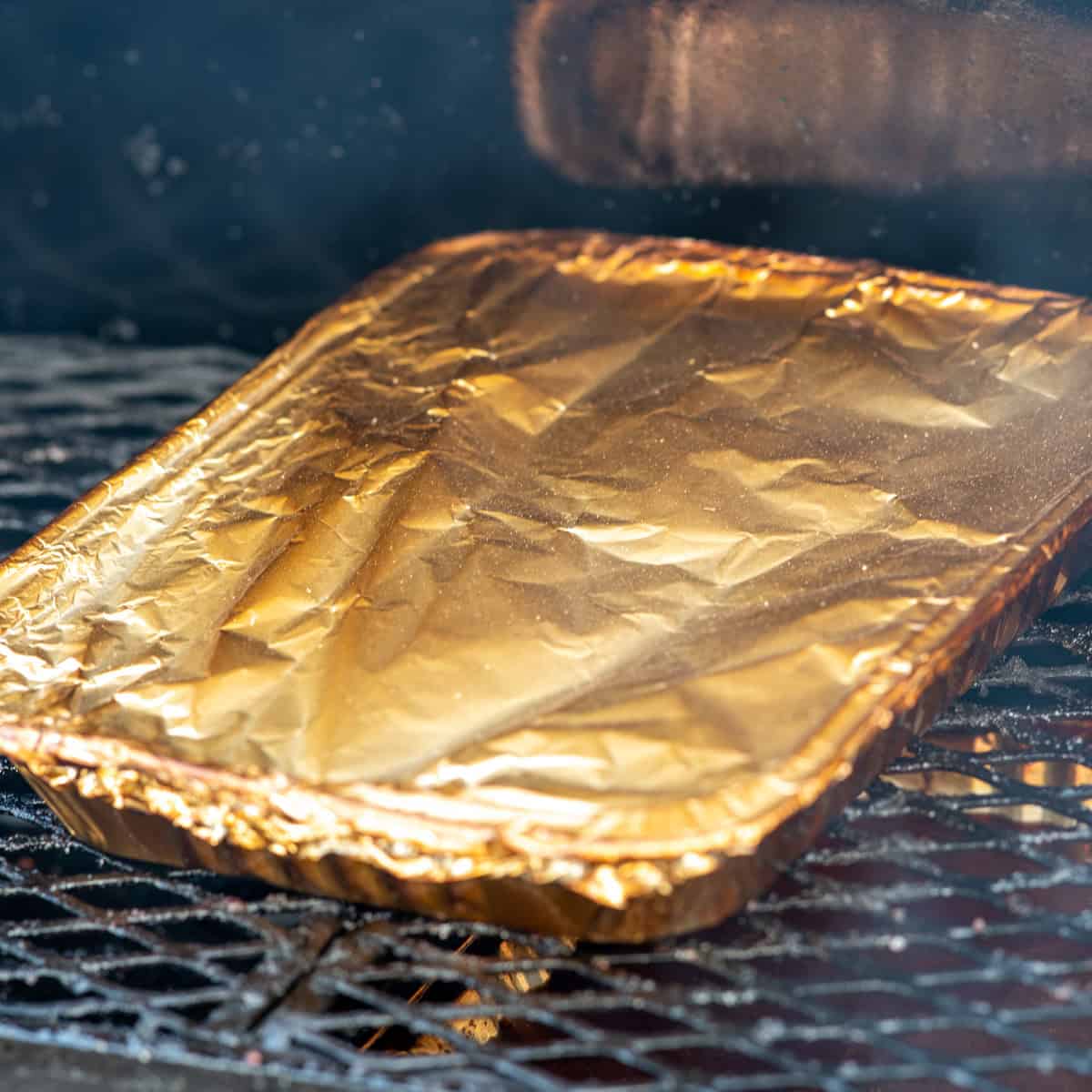 Place pork belly burnt ends in an aluminum pan. Add BBQ sauce and cover with aluminum foil.