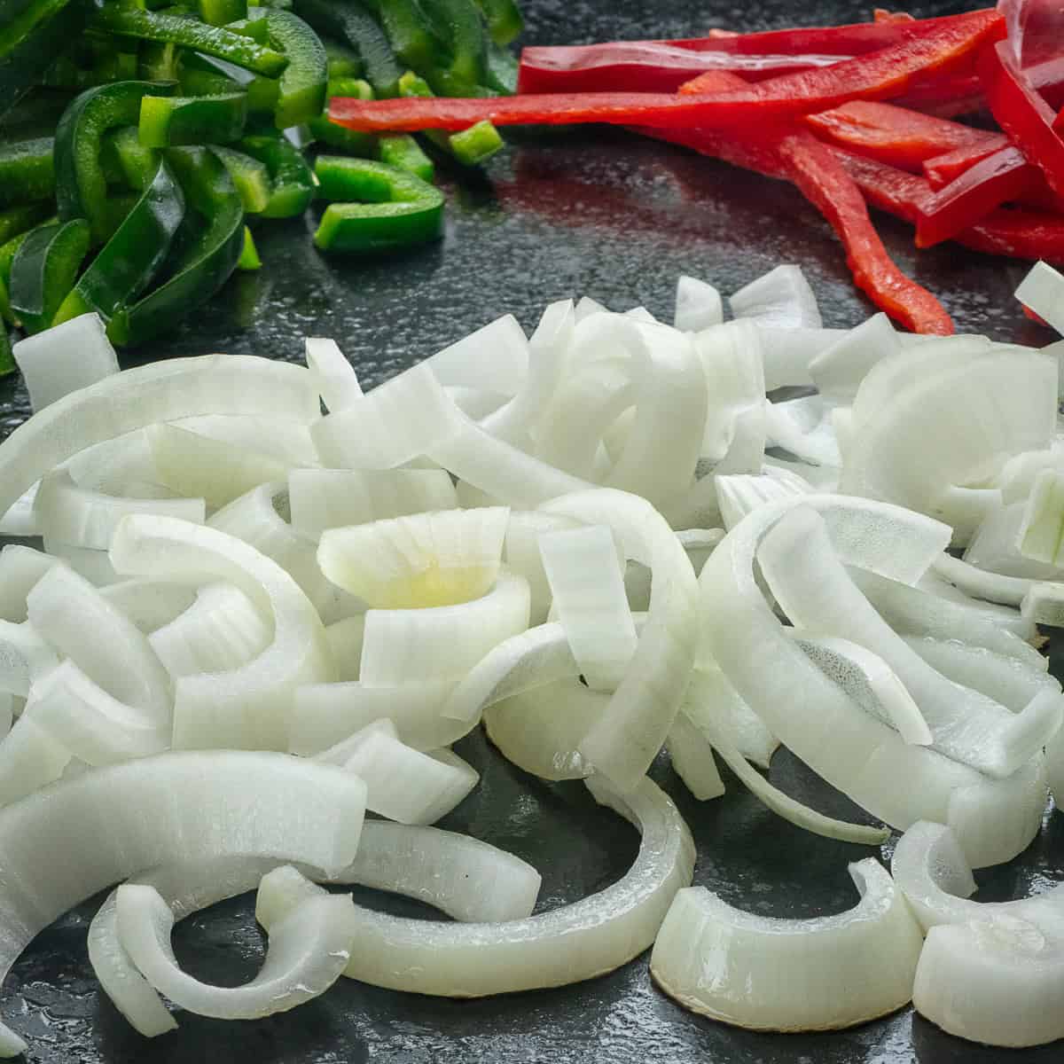 Onion, red bell peppers and poblano pepper slices on the griddle.