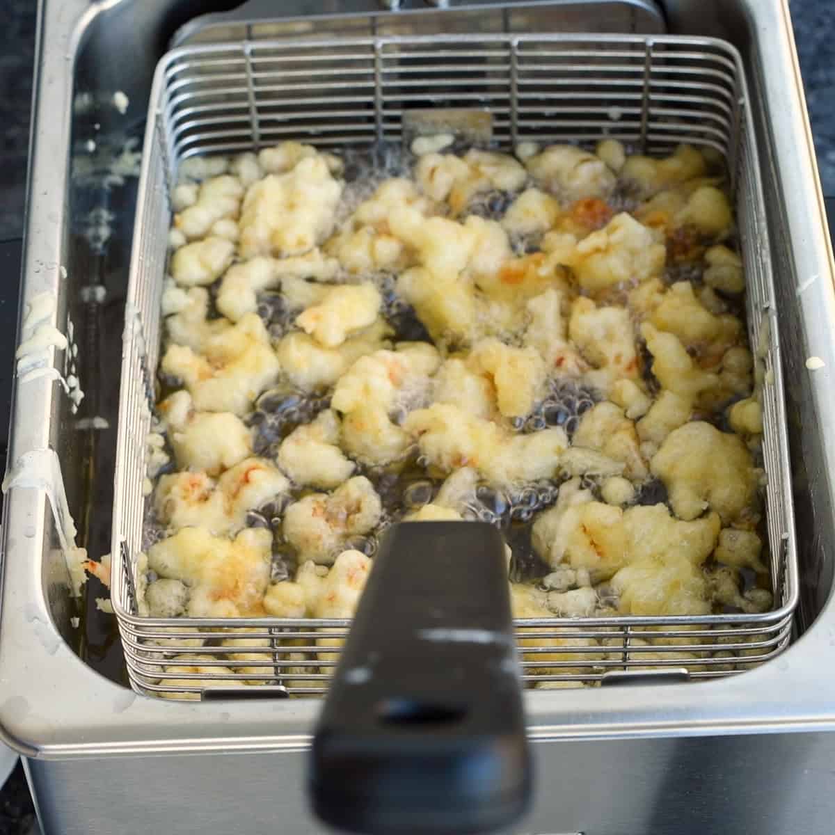 Drop the coated crawfish into the hot oil and cook until golden brown.