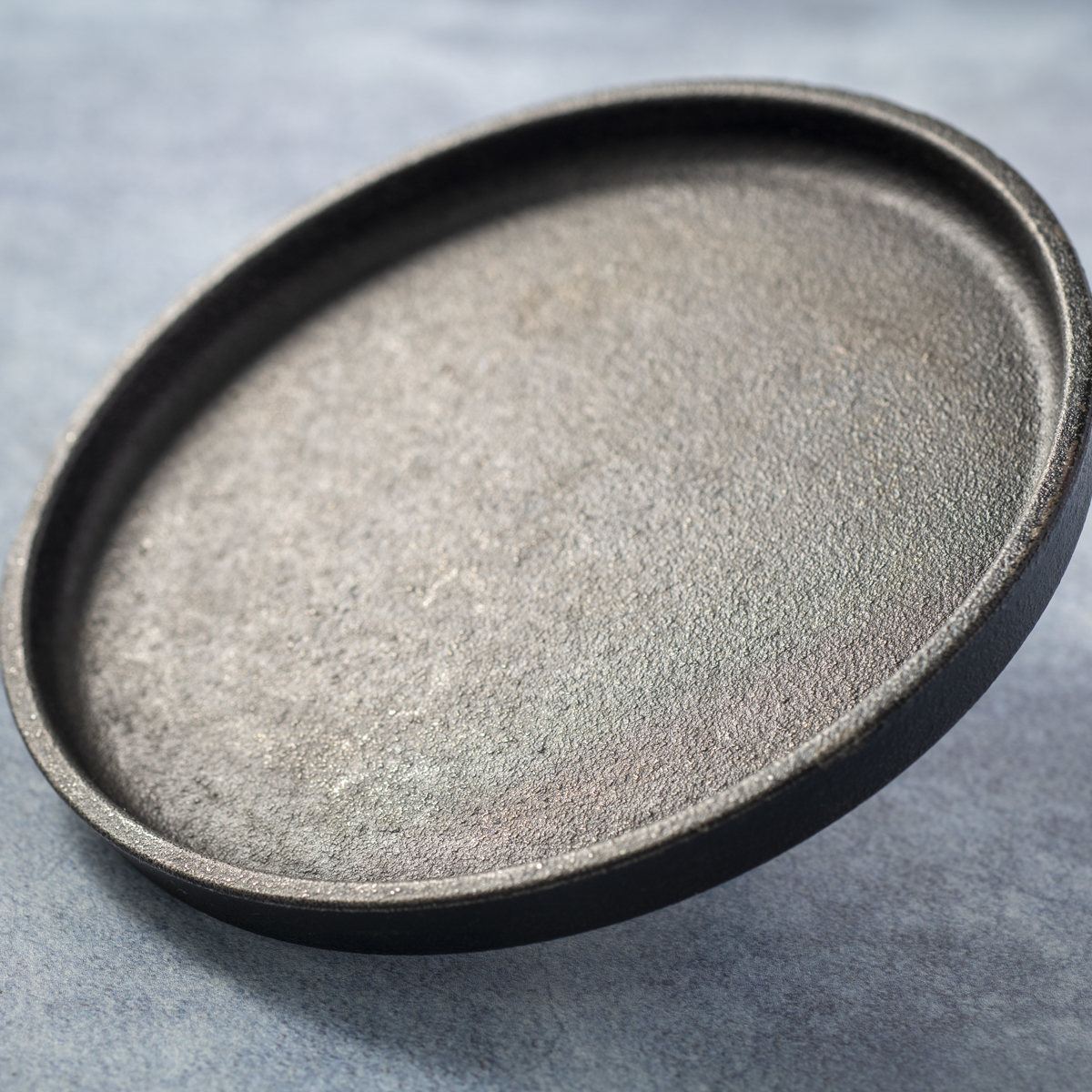 Lodge cast iron burger press with a raised lip.