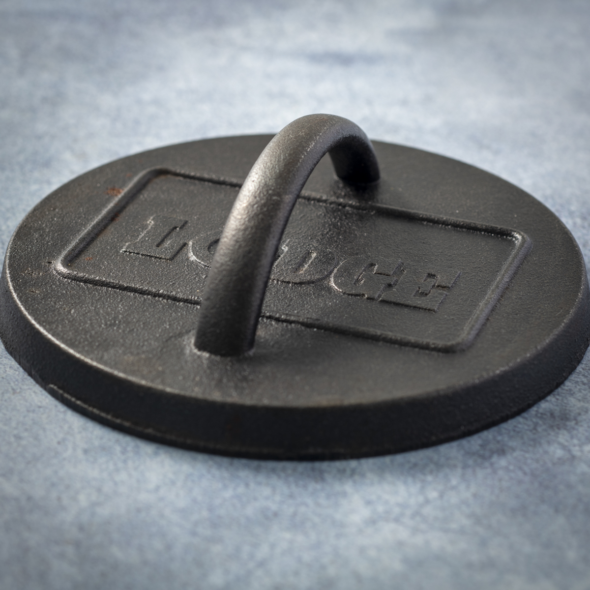 Lodge cast iron burger press with a raised lip.