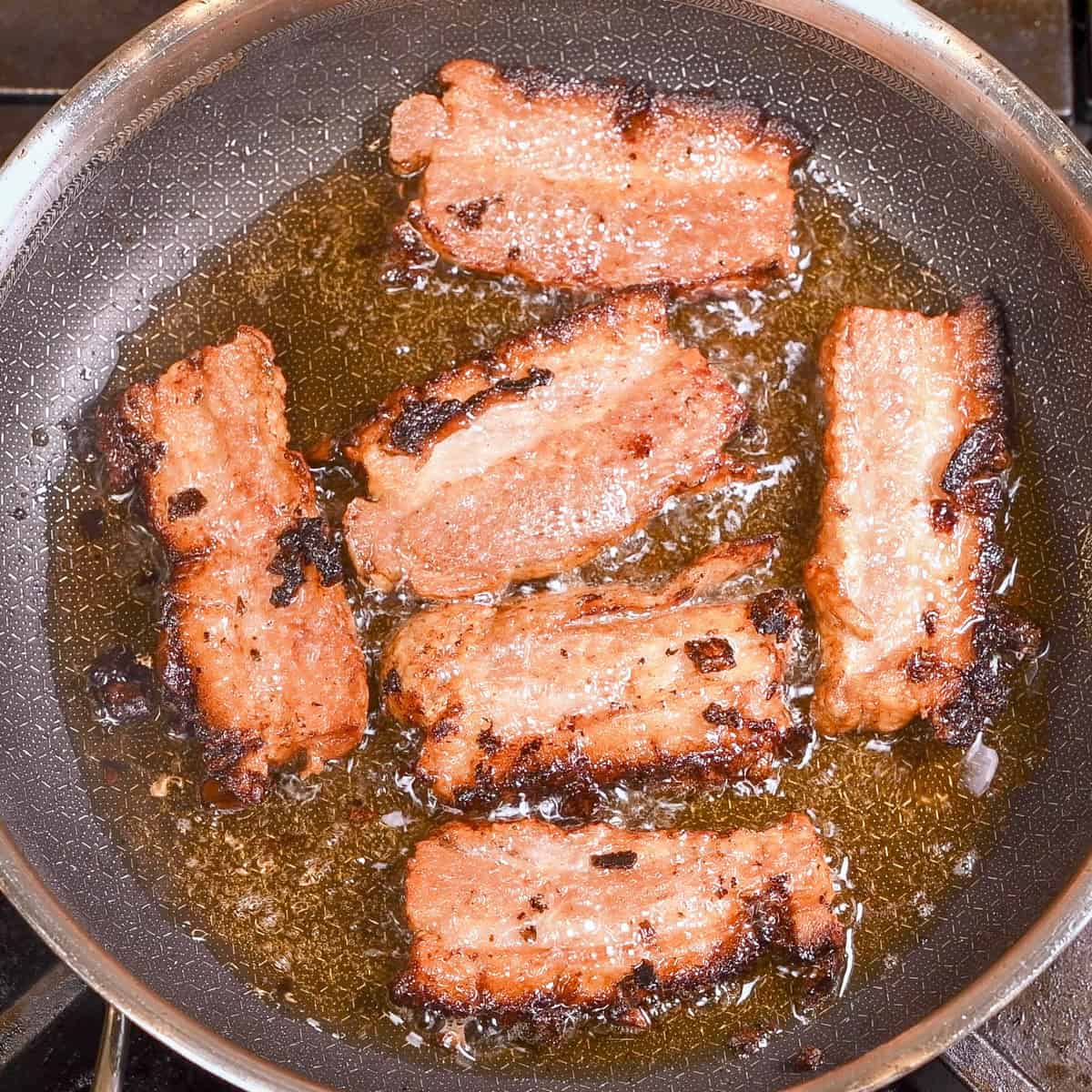 Pan fry the strips of pork belly until crispy.