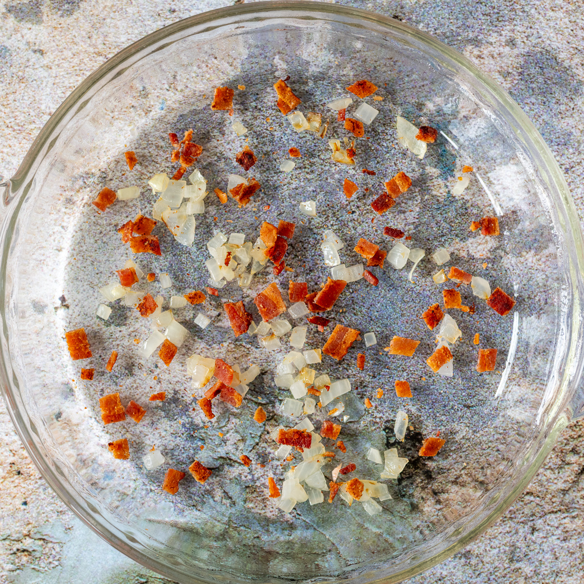 Add a layer of onion and bacon to the bottom of a prepared pie dish.