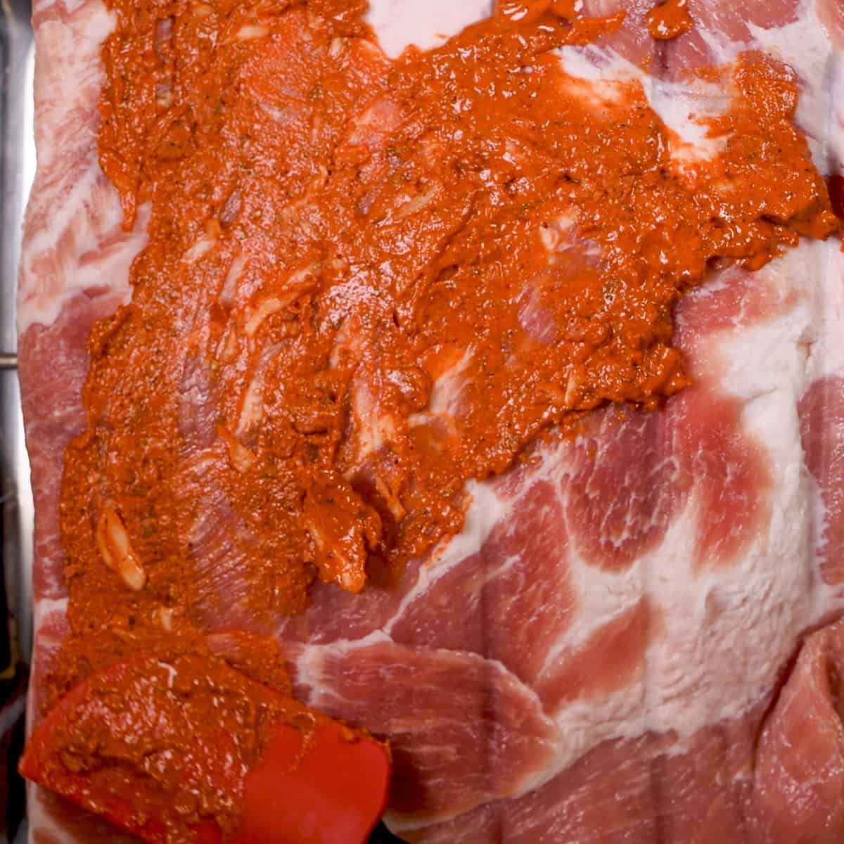 Rub the annotto paste on both sides of the pork belly.