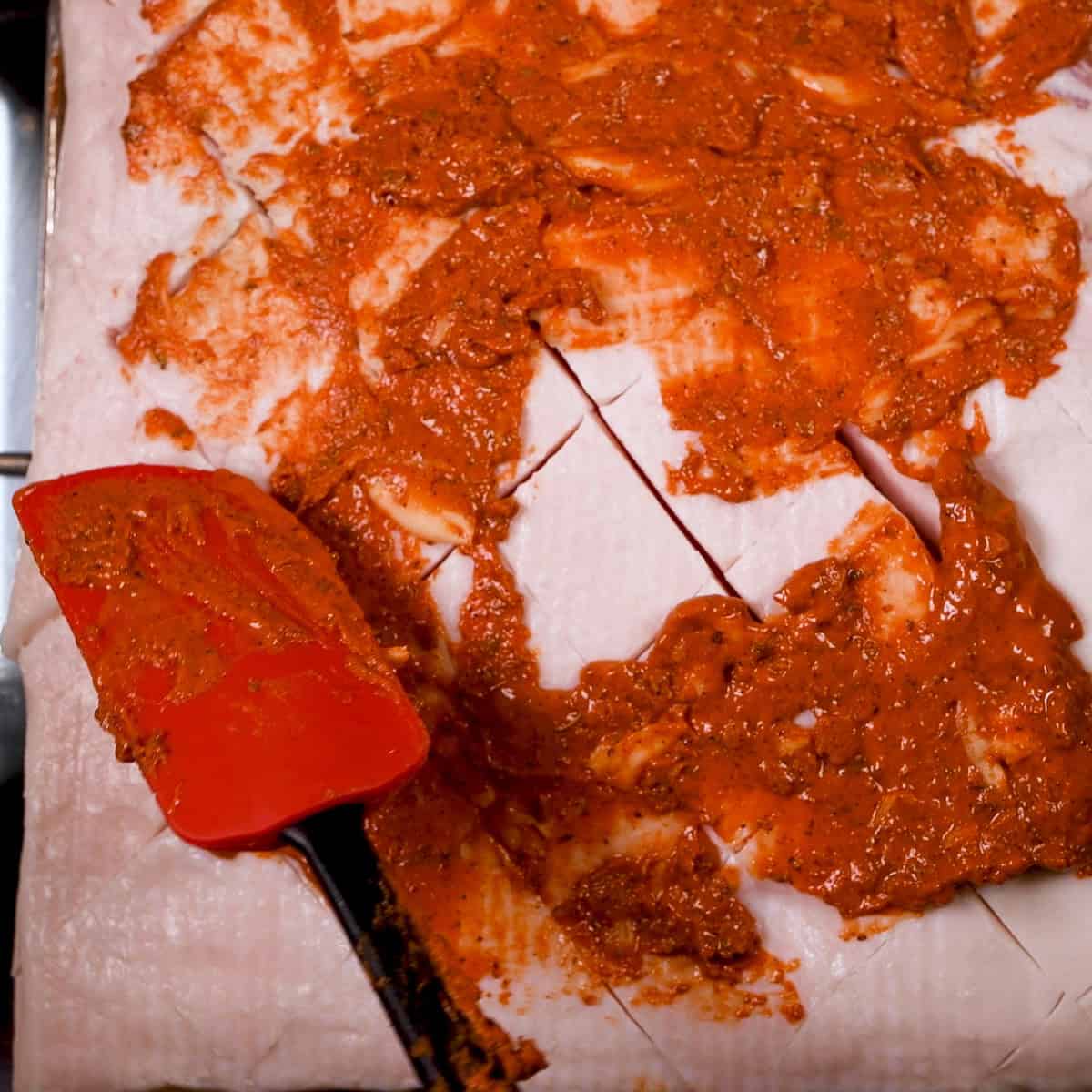 Rub the annotto paste on both sides of the pork belly.