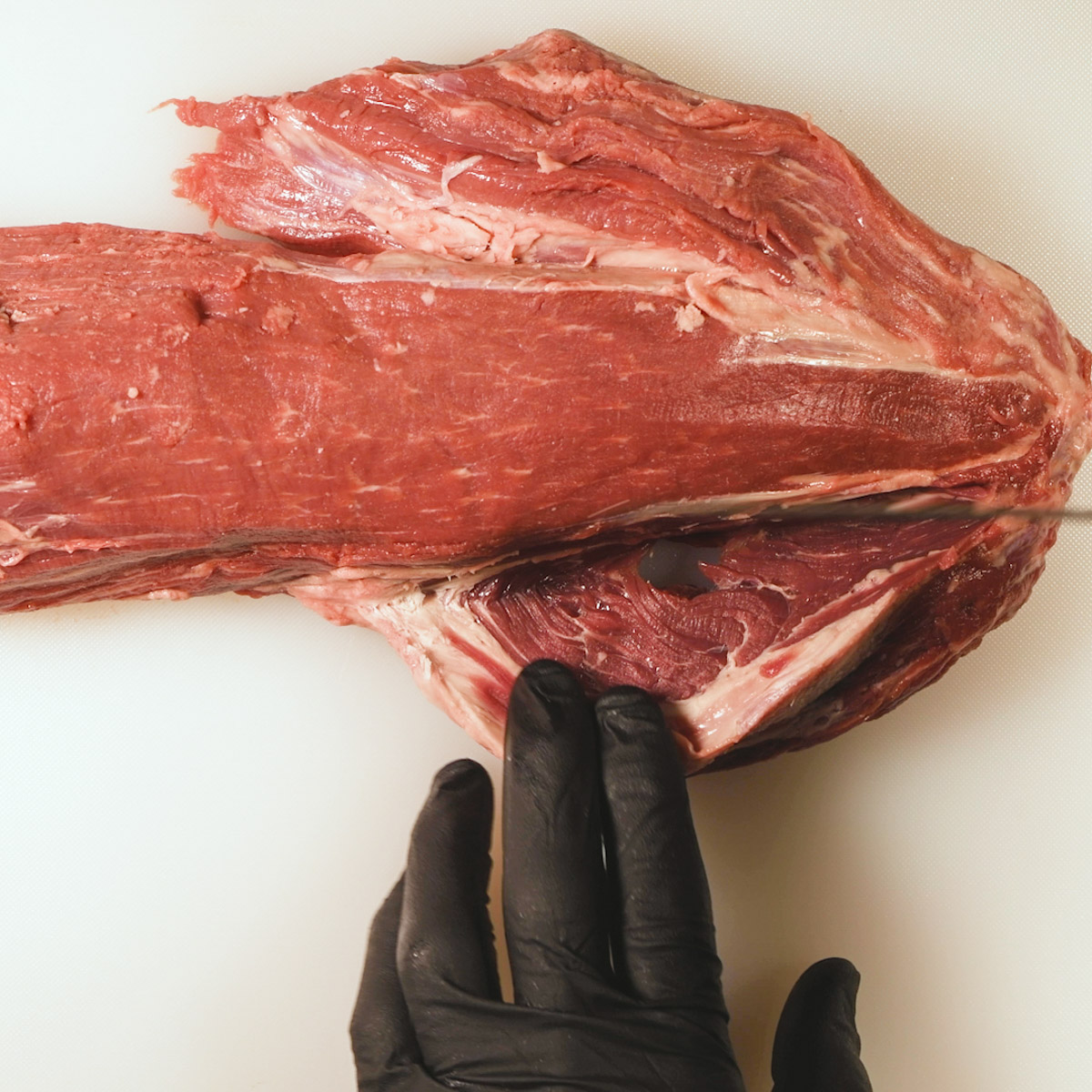 Trim head section of beef tenderloin.